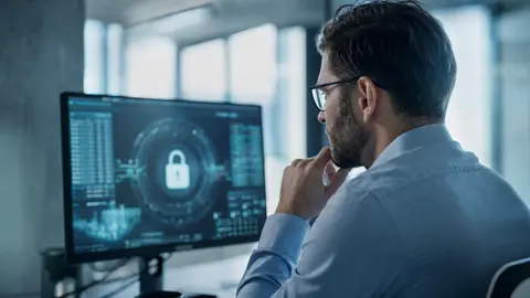 IT-Sicherheit im Unternehmen: Fachkraft prüft ein Security-Dashboard mit Schloss-Symbol am Bildschirm