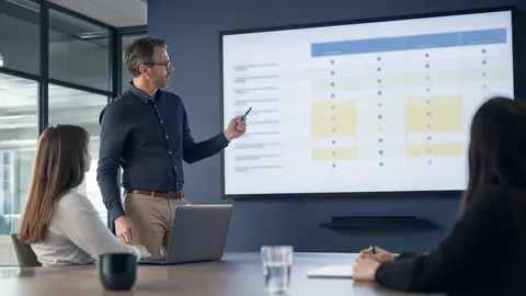 Microsoft-365-Lizenzplanung: Fachkraft vergleicht die Plan-Stufen als übersichtliche Matrix am großen Bildschirm