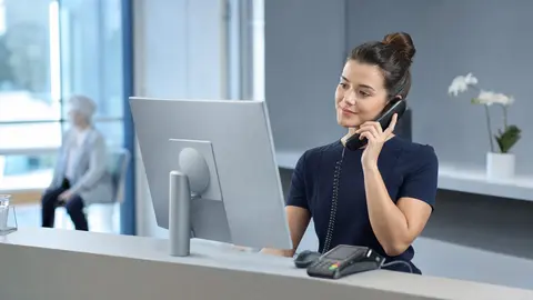Telematikinfrastruktur in der Arztpraxis: Empfangscomputer mit Kartenterminal in einer hellen, vertrauenswürdigen Praxisumgebung