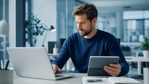 Microsoft 365 im Arbeitsalltag: Laptop und Tablet auf einem aufgeräumten Schreibtisch in einem hellen Büro