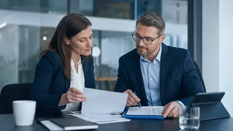 Cyberversicherung fürs Unternehmen: zwei Fachleute prüfen die IT-Sicherheitsanforderungen an einer Checkliste