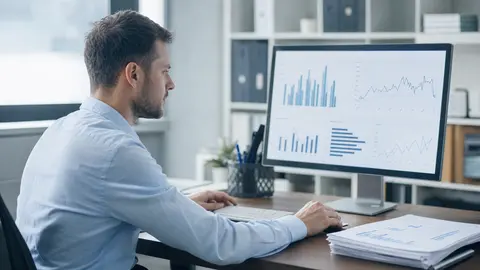 Reporting automatisieren: Controller prüft einen automatisch erzeugten Bericht mit Diagrammen am Monitor, der ausgedruckte Wochenbericht liegt daneben