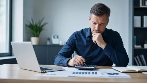 IT-Betreuung und Kosten: Unternehmerin kalkuliert am Schreibtisch mit Taschenrechner und Laptop die Ausgaben für IT-Dienstleistungen